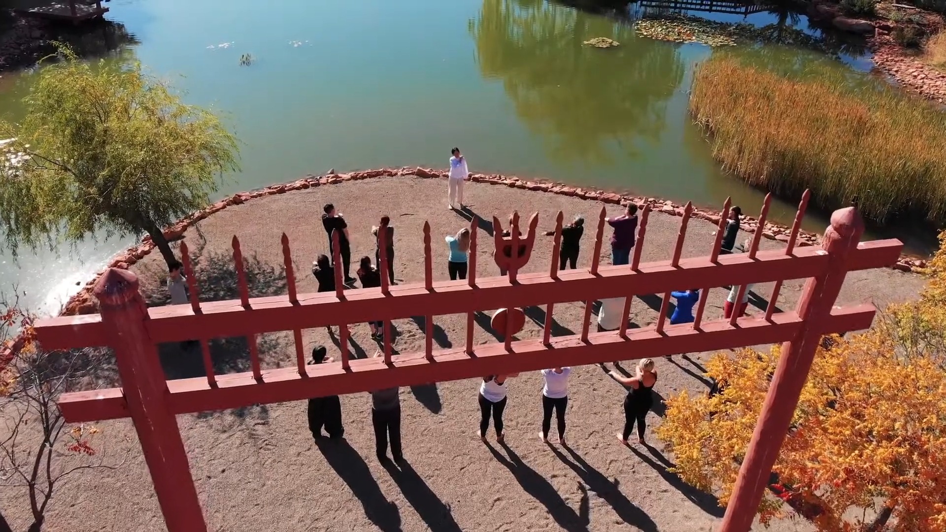 Retreat visitors practicing beside the red bridge and lake at Sedona Mago